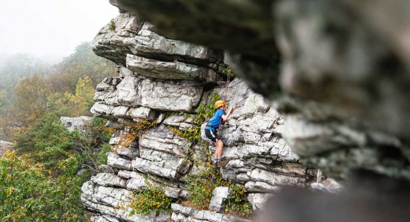 a student scales a rock wall on a rock climbing trip near DC